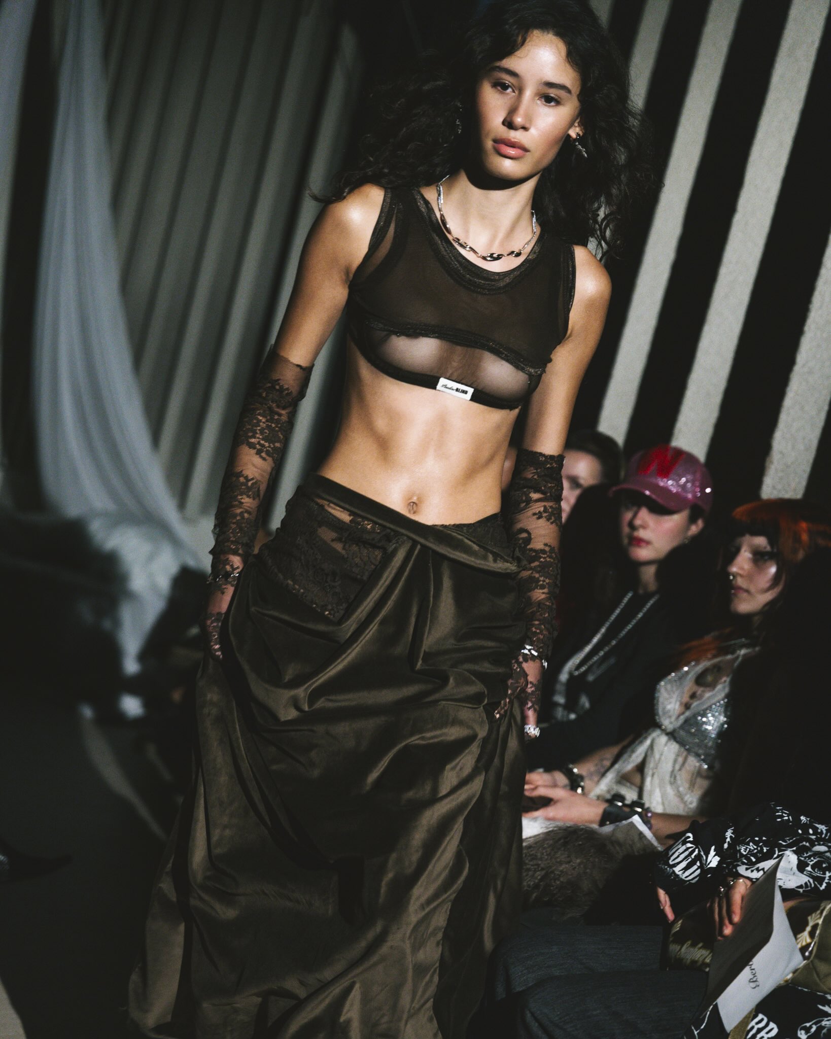 Runway photograph of Pauline Blind’s Blasphemous Bodies collection at Amsterdam Fashion Week, featuring models in veils, layered garments, and symbolic accessories.