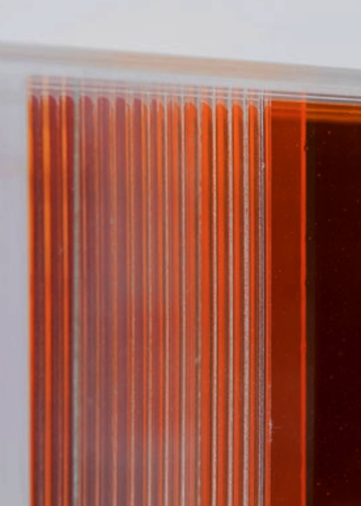 Close-up of Christiane Grimm’s glass artwork showing layered orange and red ribbed glass panels with translucent reflective edges.